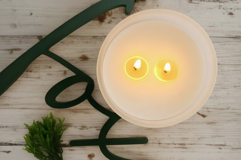 two wicks candle in a frosted glass jar on a wooden surface with seaweed garland. text says 'fox'