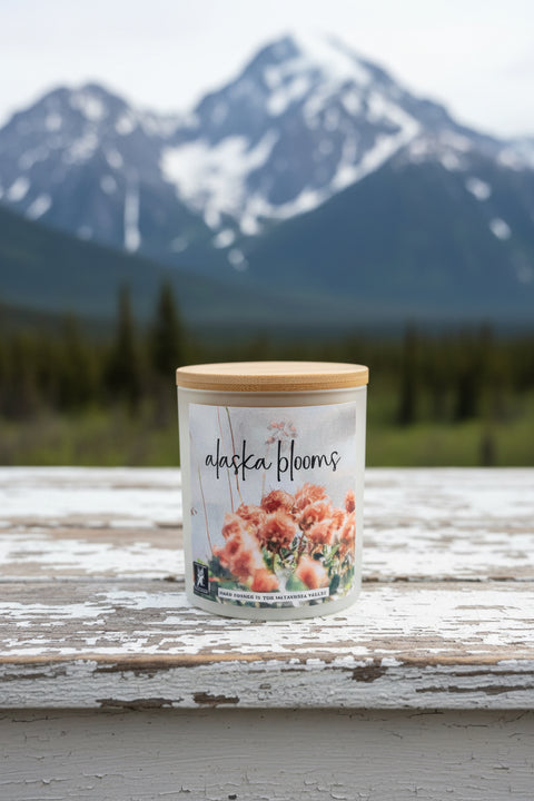 Jar labeled 'Alaska Blooms' on a wooden surface with mountains in the background
