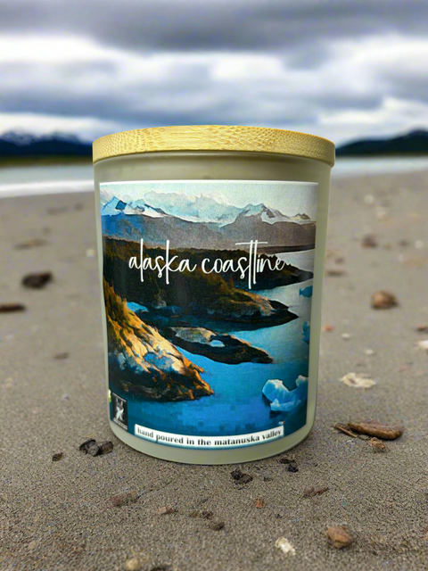 Candle with Alaska Coastline label on a sandy beach