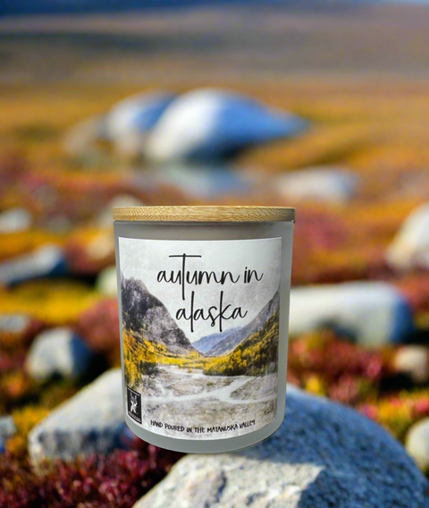 Candle with 'Autumn in Alaska' label against a scenic background