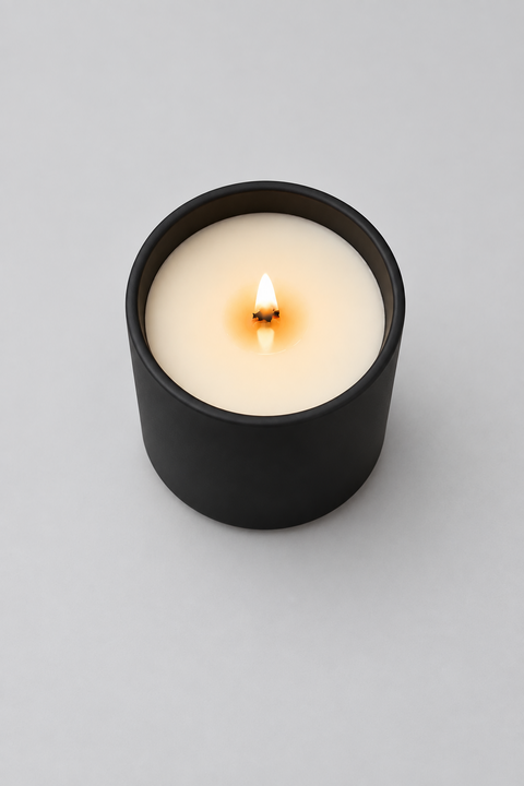 Candle in a matte black glass jar; wood wick burning