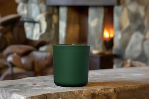 Candle in a pine candle container on a wooden surface, blurred background of a cozy alaskan lodge room.