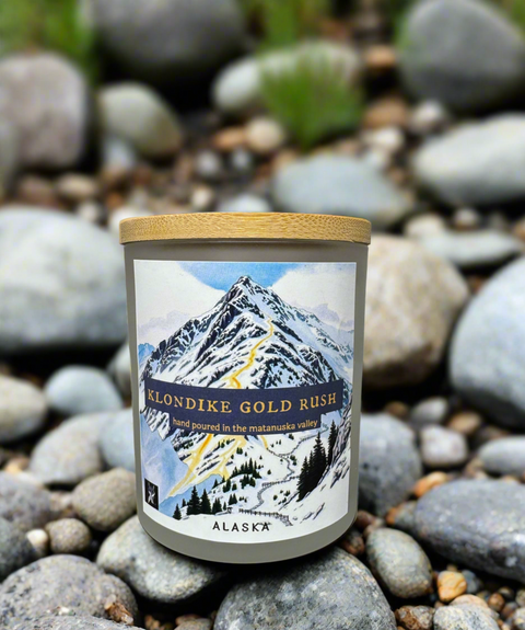 Candle with a mountain-themed label on a creek bed