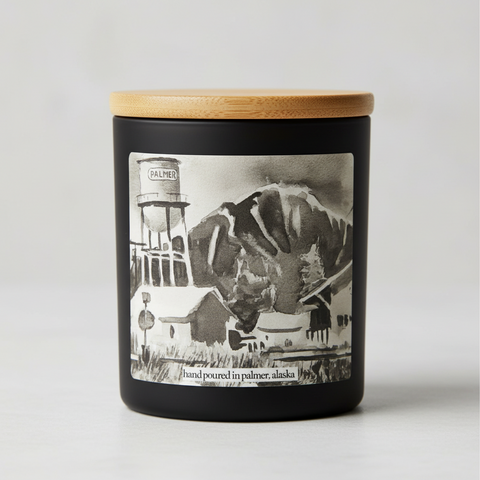 A watercolor art candle label of the Palmer Water Tower in Alaska, featuring a large tank on top of a mountain with a small town in the foreground.
