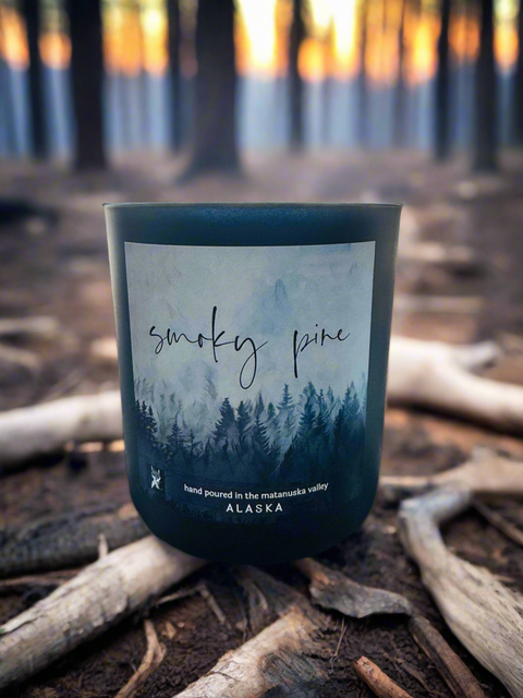 SMOKY PINE COCONUT WAX CANDLE SITTING IN ALASKA FOREST