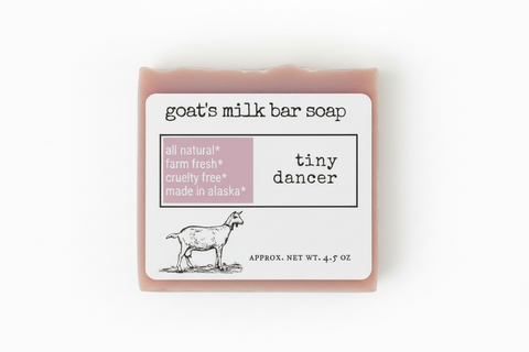 Product label for goat's milk bar soap named 'tiny dancer' by the brand 'tiny dancer'. The label features a white background with black text, a dusty pink block highlighting key certifications, and a black line drawing of a goat.