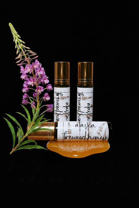 Three perfume roll on bottles labeled 'Alaskan Fireweed Honey' on a black background