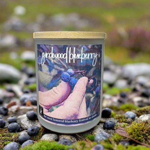 Candle labeled 'Girdwood Blueberry' on a natural background with blueberries and stones.