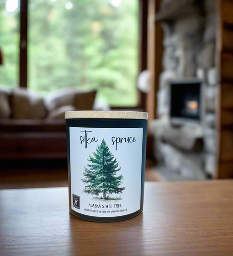 Candle labeled 'Silka Spruce' on a table with a blurred background of a living room.