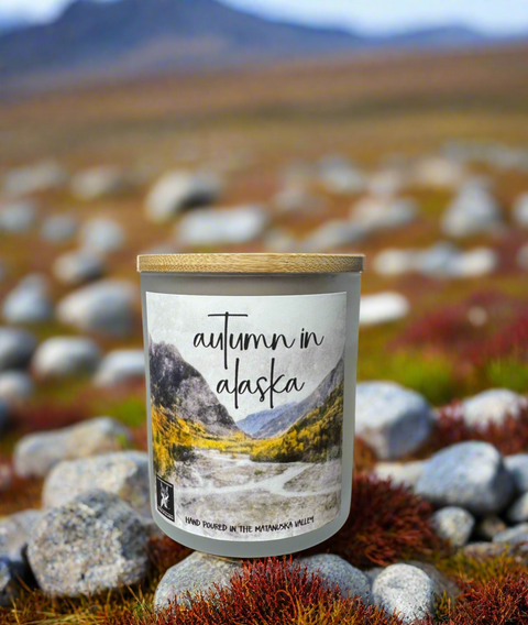 Candle labeled 'Autumn in Alaska' with a scenic label against a natural background.