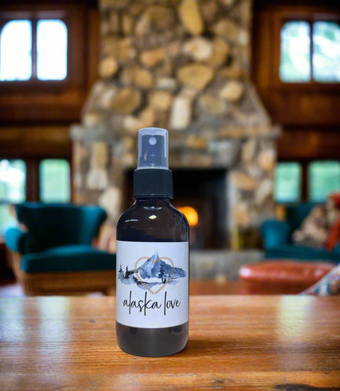 Bottle of 'Alaska Love' spray on a wooden table with a stone fireplace background