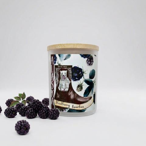 Candle with a blackberry bourbon label and blackberries to the left.