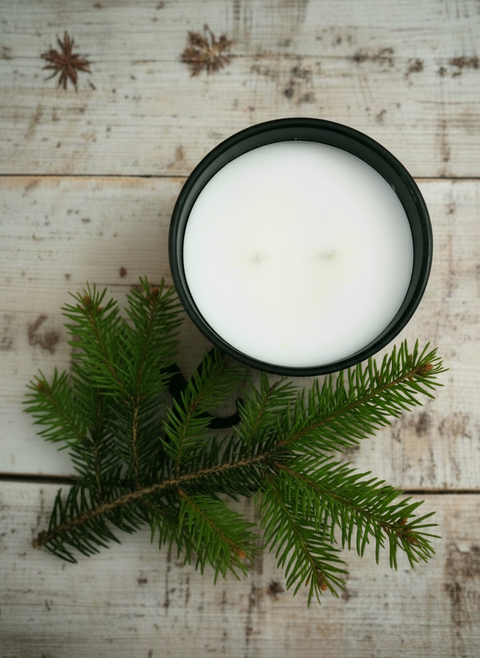 White candle in a black container on a wooden surface with the word 'fox' written in black.