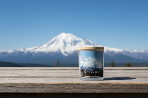 Candle with Denali mountain view label on a wooden surface with Denali in the background
