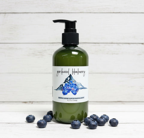 Green bottle with pump and blueberry label on a wooden surface with blueberries around