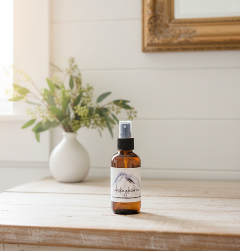 "Alaska Glacier Ice linen and room mist in amber spray bottle on a modern bathroom counter with tropical plant, Grey Fox Candles"