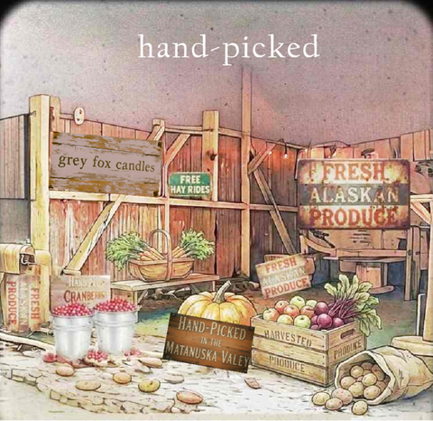 Vintage-style illustrated sign collage with rustic wooden fencing, crates of apples and potatoes, baskets of greens, and handwritten signs including 'hand-picked', 'Fresh Alaskan Produce', and 'Grey Fox Candles'.