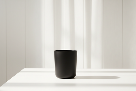 Black candle jar on a white surface with a white background