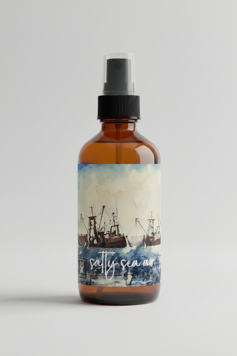  Salty Sea Air linen and room spray in an amber glass bottle with black pump top, featuring a watercolor fishing boat label