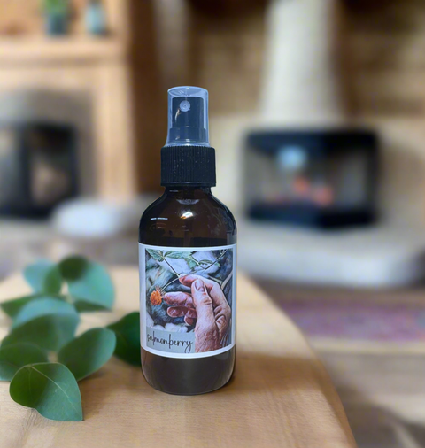 Bottle of 'SALMONBERRY' linen spray on a wooden surface with blurred background