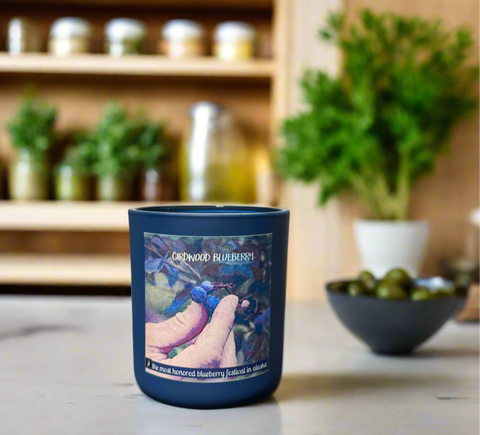 Blue candle with a label featuring blueberries on a kitchen counter.