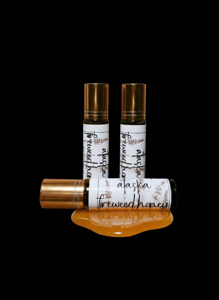 Three perfume roll on bottles labeled 'Alaskan Fireweed Honey' on a black background