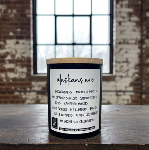 Candle with a label on a wooden surface against a brick wall background