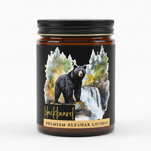 A jar of Blackbeard Premium Beeswax Lotions with a black lid and a black label featuring a watercolor illustration of a black bear, waterfall, and trees.