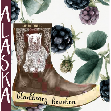 Candle labeled 'Blackbeary Bourbon' with a bear illustration on a boot, surrounded by berries and leaves.
