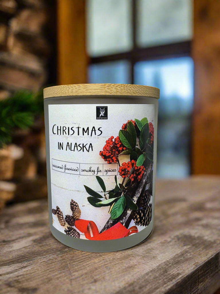 Candle with a label featuring Christmas-themed graphics on a wooden surface.