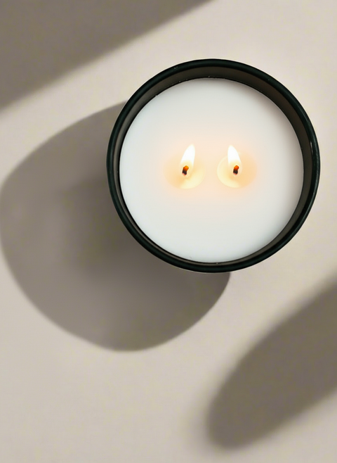 White candle in a black matte jar on a light background