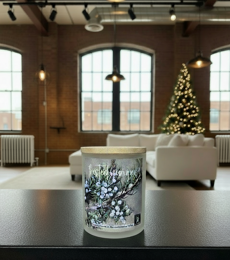 Candle with decorative label on a table in a modern room with a Christmas tree