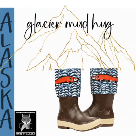 A pair of brown rubber mud huggers with blue and white patterned cuffs featuring red fish illustrations, displayed on a white background with 'glacier mud hug' text, a blue vertical 'ALASKA' banner, and a small 'Made in Alaska' logo.