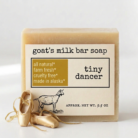Product label for goat's milk bar soap named 'tiny dancer' by the brand 'tiny dancer'. The label features a white background with black text, a gold block containing product benefits, and a black line drawing of a goat.