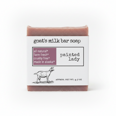 Product label for goat's milk bar soap named 'painted lady' by scent/variant 'all natural'. Features a white background with black text, a dusty purple block with product benefits, and a black line drawing of a goat.