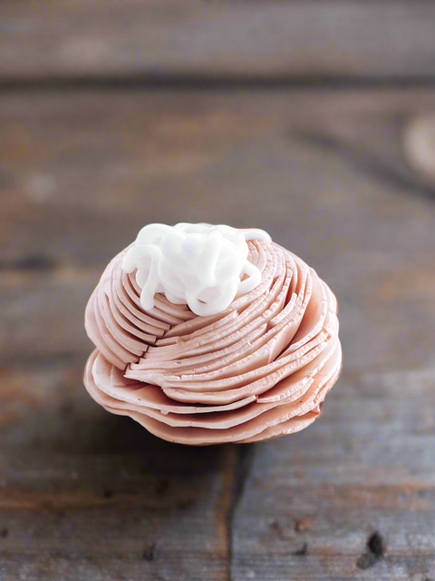 a sample of grey fox premium beeswax lotion on a wooden baby pink rose, made in alaska
