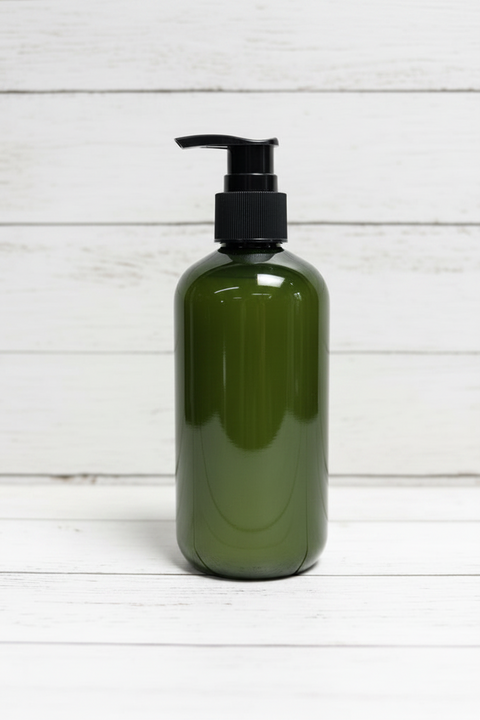 An empty olive green plastic bottle with a black pump dispenser, set against a white wood plank background.