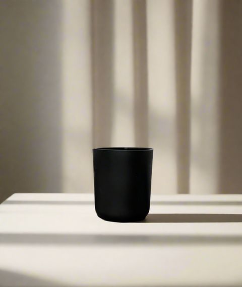 Black candle jar on a white surface with a neutral background