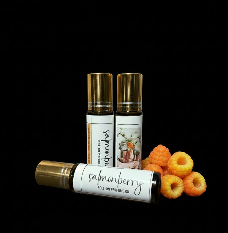 Three roll-on perfume bottles labeled 'salmonberry' with raspberries on a black background.