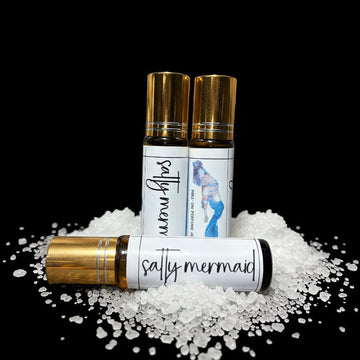Three perfume roll on bottles with 'salty mermaid' branding on a black background