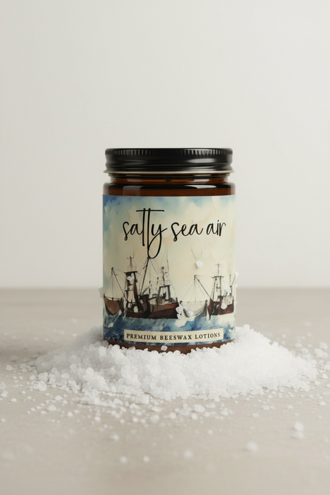  'Salty Sea Air' premium beeswax lotions by Fox Candles. The banner features a central square image of a vintage sailboat on a harbor under a cloudy sky, flanked by descriptive text on the left and right detailing the handcrafted small batches, ingredients, and skin benefits.