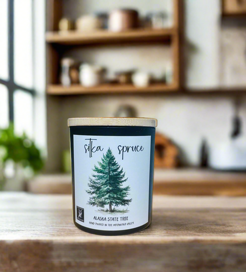 Candle labeled 'Silka Spruce' on a wooden surface with a blurred kitchen background