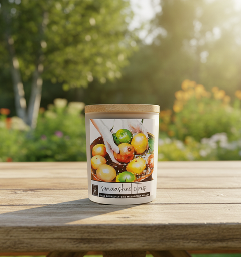 Candle jar with 'Sunwashed Citrus' label on a wooden table outdoors
