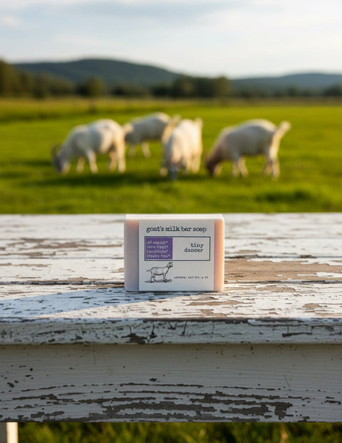 Goat's milk bar soap on a wooden surface with sheep grazing in the background