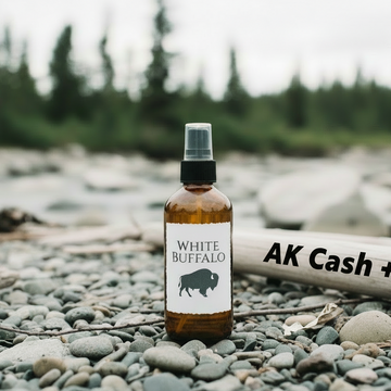 Bottle of White Buffalo product on a rocky surface with a blurred natural background
